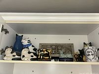 Shelf view showing full assortment of cat figurines, plaques, mug and trinket box