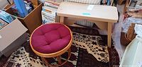 Rattan stool with red cushion beside small light-wood bench on patterned rug