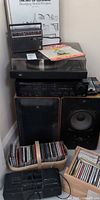 Stacked audio components, speakers, CDs, Atari console visible