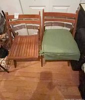 pair of wood folding chairs, one with green cushion