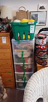 Front view showing plastic five-drawer tower filled with yarn, green crate with more supplies on top, tins of supplies adjacent