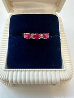 Front view of ring showing three rubies and diamond accents in setting