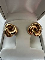 Front view of both gold swirl knot earrings in box