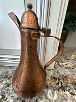 Full view of hammered copper ewer showing lid, handle and spout