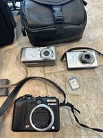 Close of three digital cameras, small case and SD card