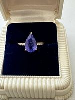 Ring in presentation box showing pear tanzanite and diamond shoulders