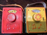Front view of both Fisher-Price pocket radios showing color, knobs, song labels and grills
