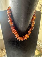 Front view of amber nugget necklace on display bust
