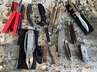 Overall lot layout showing all knives, multi-tools and buckle on granite surface