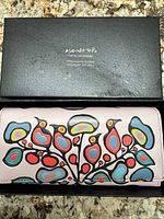 Wallet in open box showing floral exterior design and box lid branding