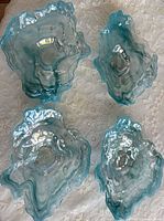 Four blue iridescent oyster shell glass dishes displayed on lace cloth