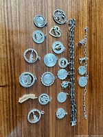 Overview of two bracelets and seventeen charms laid out on wood surface