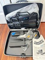 Camcorder, charger, battery, cables, manual inside open carrying case