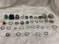 All rings laid out on fabric showing variety of sizes, metals and stone colours