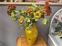 Full view of yellow vase with artificial sunflower arrangement