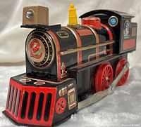 Front three-quarter view of Shinsei tinplate locomotive showing numbered nose, grill, wheels, and side rods