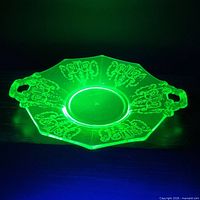 Dish glowing bright green under UV light showing uranium content and etched design