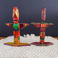 Both carved figures side by side front view on mat