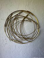 Full view of circular gold metal sculpture mounted on textured wall