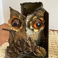 Front view of one owl bookend showing amber eyes, leaves, vase
