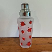 Shaker assembled showing frosted glass body with red starbursts and chrome lid