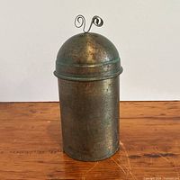 Full view of cylindrical brass canister with lid in place