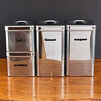 Front view of all four chrome canisters showing labels and lids