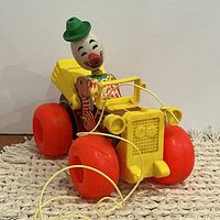 Front three-quarter view showing clown driver, yellow hood, red wheels, pull string