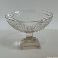 Side profile of pressed glass pedestal bowl showing ribbed body and square base
