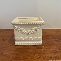 Front view of square cream planter showing leaf relief and pedestal base