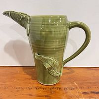 side profile of green glazed pitcher showing leaf at spout and handle