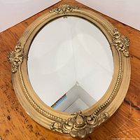 Front view of oval gilt wall mirror showing full frame and glass