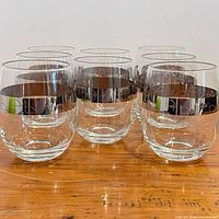Front angled view of all eight tumblers showing silver overlay bands and clear glass bodies