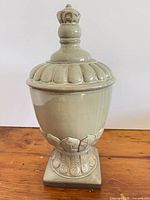 Front view of glazed ceramic urn with lid on wooden surface