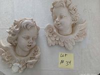 Both cherub wall plaques side by side showing overall condition and size reference