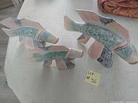 Three carved wooden fish sculptures on tabletop, various angles