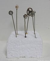 Six hat pins inserted in foam block showing heads