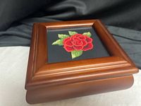 Three-quarter view of closed mahogany jewelry box showing rose needlepoint lid