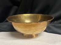 Oblique view of brass pedestal bowl showing shape and patina