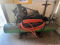 Full view of compressor on floor with hose on top