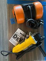Top view showing DeWalt angle grinder with wrenches, manual, and orange bench grinder body