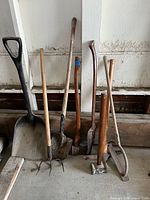 All seven garden tools leaning against wall