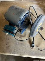 Overall view of bench grinder showing housing, grinding wheel, power cord and base