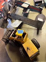 Yellow Tonka loader next to wood airplanes and fan blades