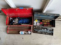 Toolboxes open showing contents: wrenches, coil springs, spray can
