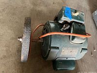 Overall view of bench grinder showing housing, wheel, switch, cord