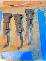 Three vintage adjustable wrenches laid side by side