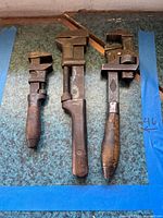 Three vintage adjustable wrenches laid side by side on surface