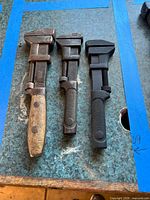 Top-down view of three vintage adjustable wrenches on tabletop