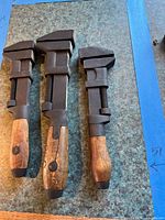 Three vintage adjustable monkey wrenches on tabletop